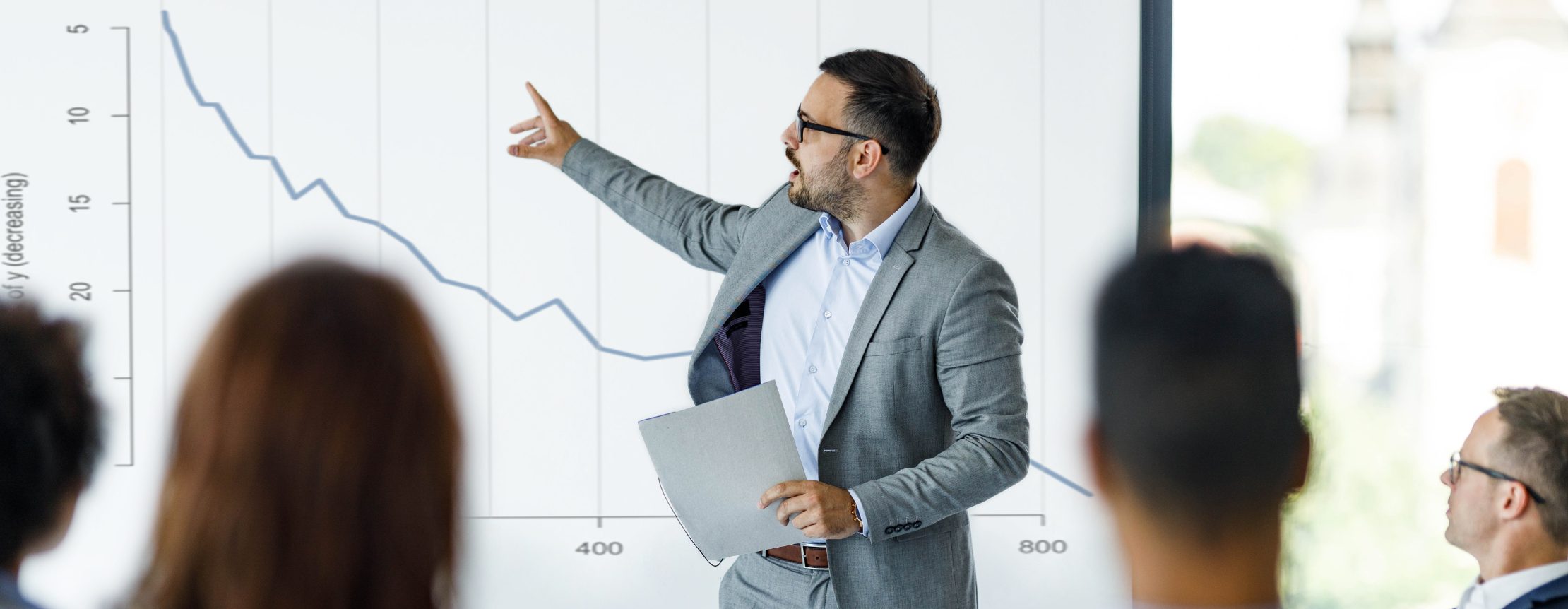 Presenter at head of seminar pointing at graph